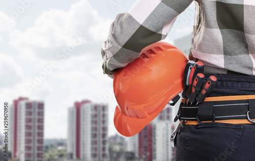 A female construction worker with safety helmet against city background