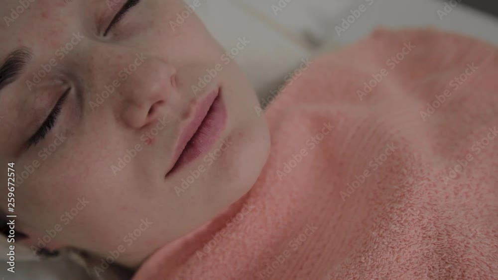 Beautiful young woman in bathrobe lying and waiting facial care procedure at luxury spa salon