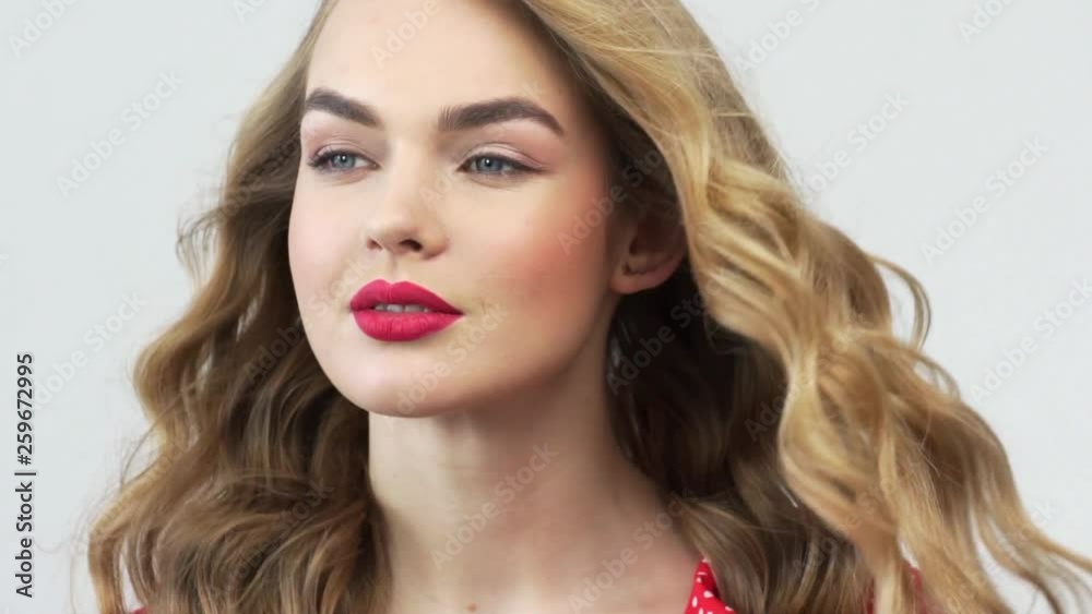 Beautiful woman with long curly hair. Attractive fashion model with a red lipstick on the lips. Closeup caucasian face of a girl. Slow motion footage. Sexy blonde. Beautiful woman with long curly hair. Attractive fashion model with a red lipstick on the lips. Closeup caucasian face of a girl. Slow motion footage. Sexy blonde.