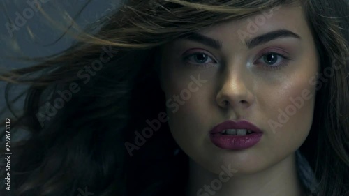 Beautiful woman with long curly hair. Attractive fashion model with a purple lipstick on the lips.  Closeup caucasian face of a girl. Slow motion footage. Sexy brunette lady.  