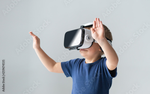 Portrait of happy boy in a virtual reality headset. Attractive kid using vr goggles at home. Entertainment technology and generation Z concept.