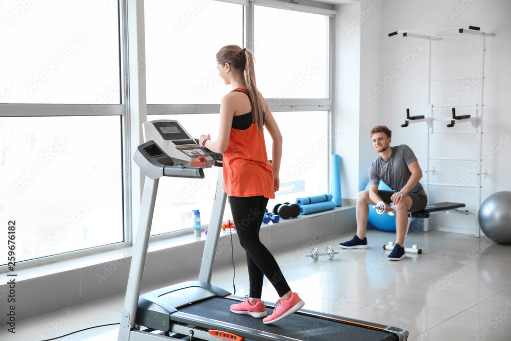 Fototapeta premium Sporty young woman training on treadmill in gym
