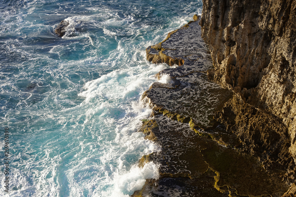 Waves crashing onto rocks at base of cliff