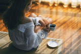 a beautiful asian woman sitting and holding a cup of hot coffee to drink on the floor in the morning
