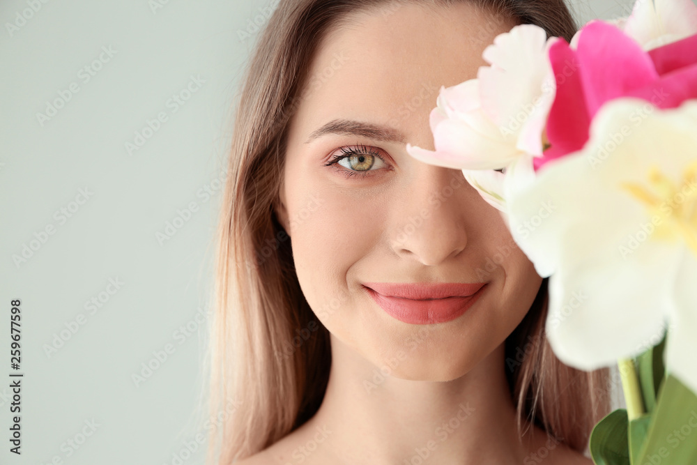 Young woman with bouquet of beautiful tulips on light background Young woman with bouquet of beautiful tulips on light background