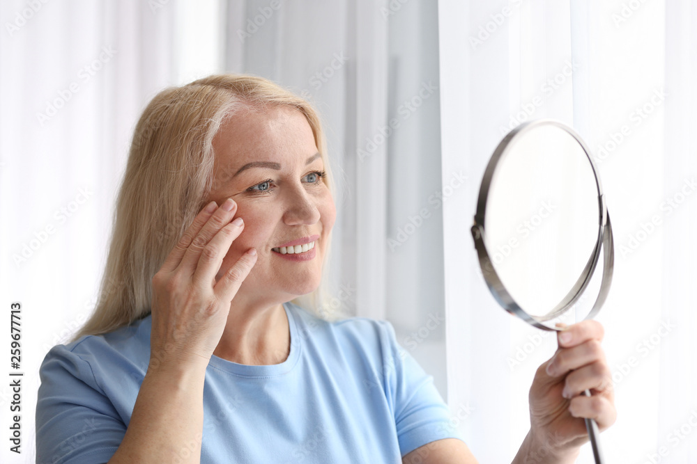 Mature woman with healthy skin looking in mirror at home Mature woman with healthy skin looking in mirror at home