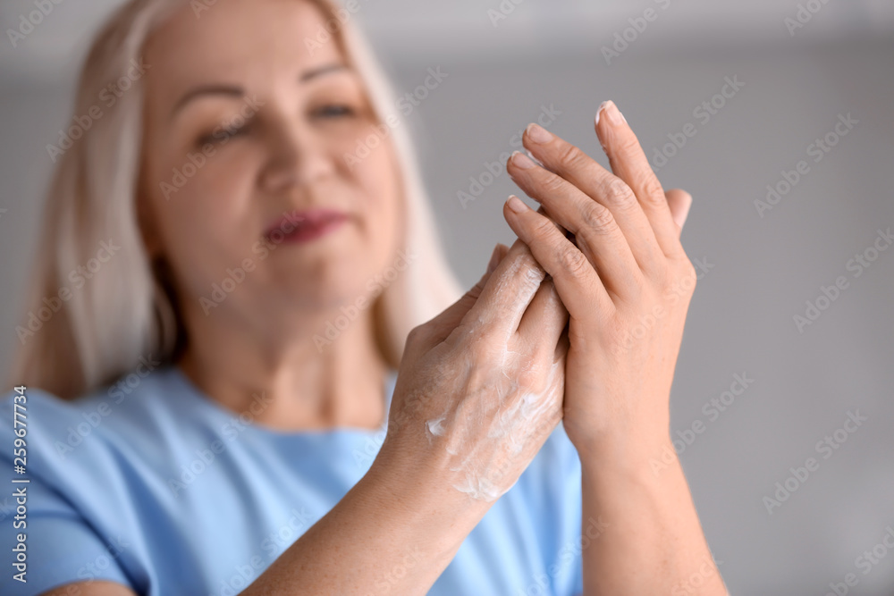 Mature woman applying hand cream at home Mature woman applying hand cream at home