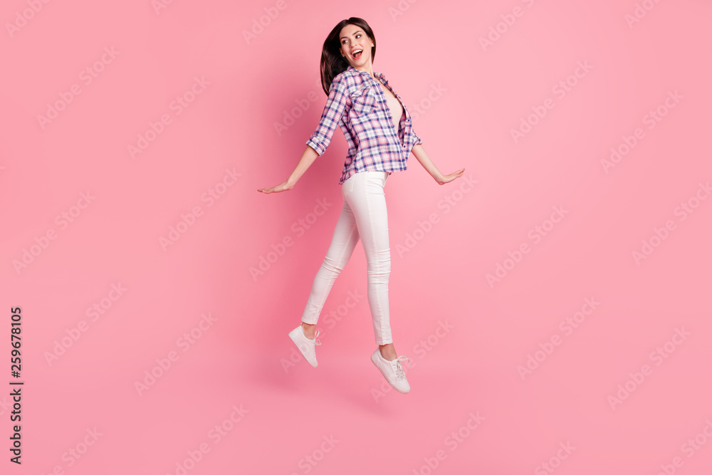 Full length side profile body size photo beautiful her she lady jump high rush hurry go along street park wear shoes casual checkered plaid shirt white jeans denim clothes isolated pink background