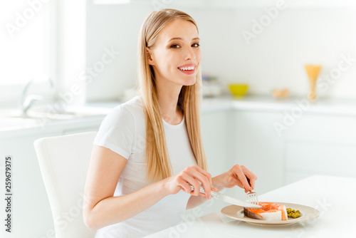 Portrait of attractive youngster millennial have lunch protein dish delicious feel satisfied content glad use fork knife silverware dressed trendy cotton clothing in big pretty kitchen