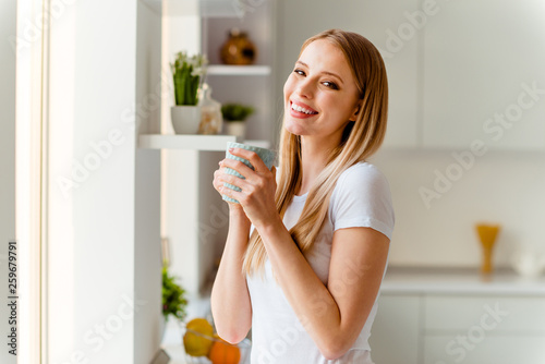 Close-up portrait of her she nice-looking cute charming lovely winsome attractive cheerful cheery straight-haired girl wearing white tshirt biting drinking beverage in light white interior room