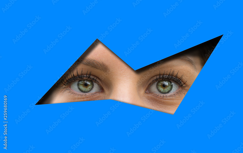 Closeup view of a woman with green eyes looking through a blue cutout