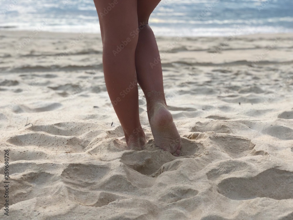 sexy women's tanned legs in the white fine sand of the unique Karon beach of Phuket on the background of the sea and the Golden sunset, a sense of pleasure and harmony sexy women's tanned legs in the white fine sand of the unique Karon beach of Phuket on the background of the sea and the Golden sunset, a sense of pleasure and harmony