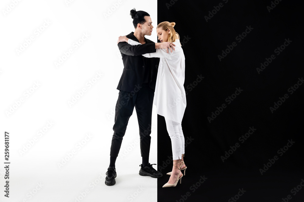 Models wearing white and black clothes hugging while posing Models wearing white and black clothes hugging while posing