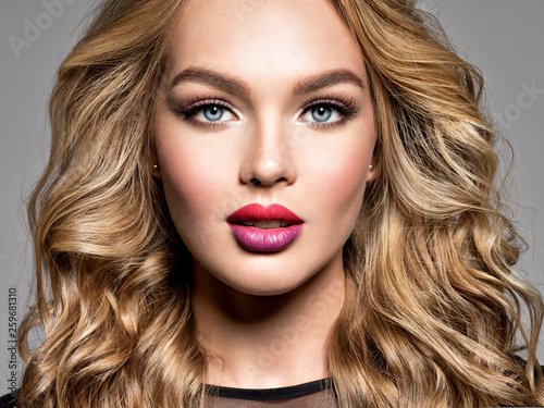 Blond woman with long curly beautiful hair. Makeup. Fashion make-up.
