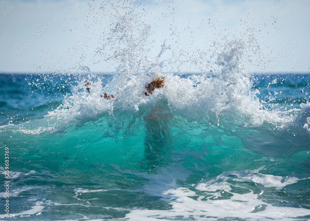 Young woman in bikini unexpected flooded with big wave