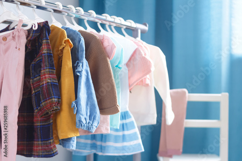 Children's cloth rack, selective focus. Pastel color children's  clothes in a Row on Open Hanger indoors. Clothes for little ladies hung in the children's room. Turquoise and pastel pink colors.