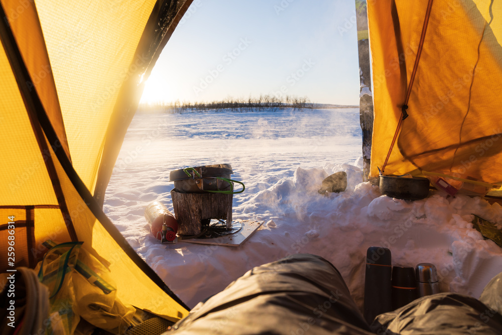 Cooking in the vestibule of a tent on a winter camping trip in Lapland