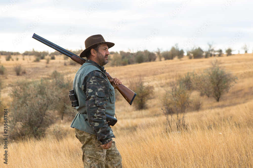 Hunter with a hat and a gun in search of prey in the steppe Hunter with a hat and a gun in search of prey in the steppe