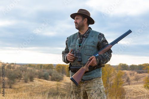 Hunter with a hat and a gun in search of prey in the steppe 