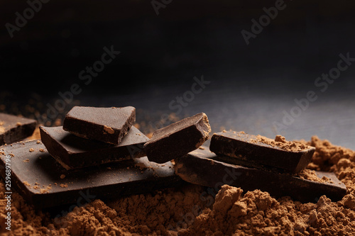 Macro shot of dark chocolate pieces and ccocoa on black background.