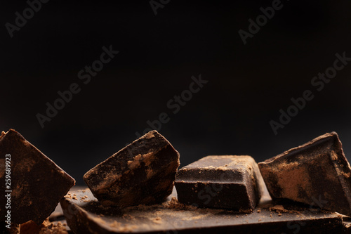 Pieces of chocolate and cocoa on dark background. Close up.
