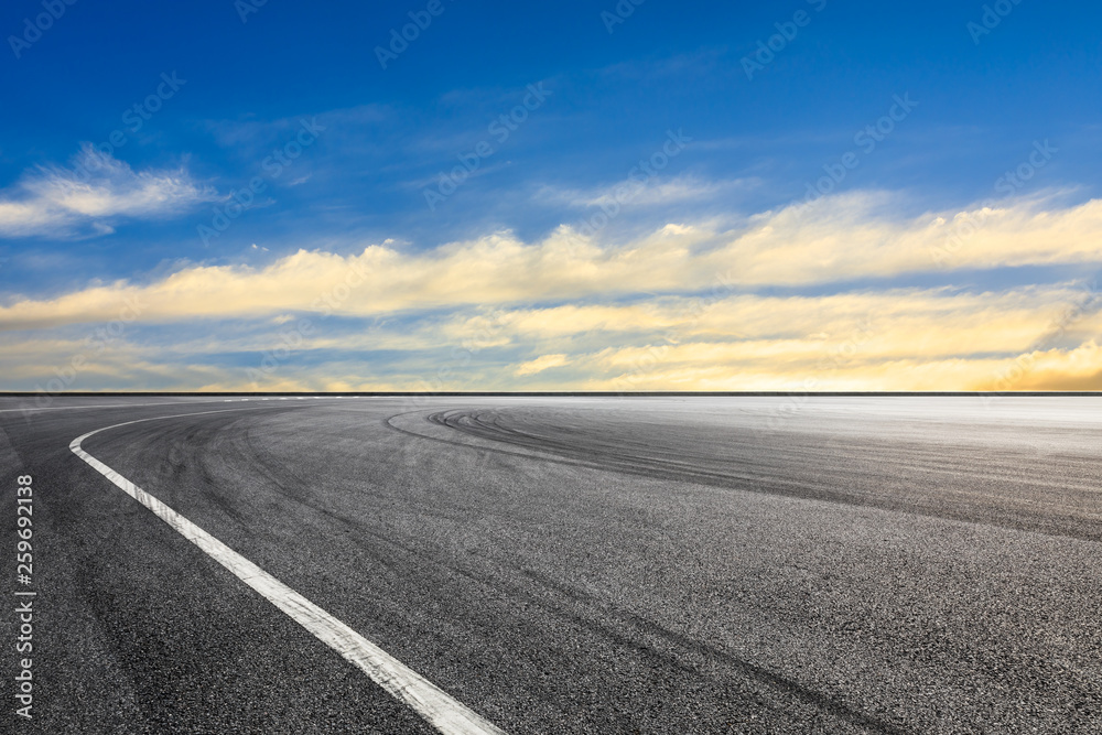 Naklejka premium Asphalt race track ground and beautiful sky clouds at sunset