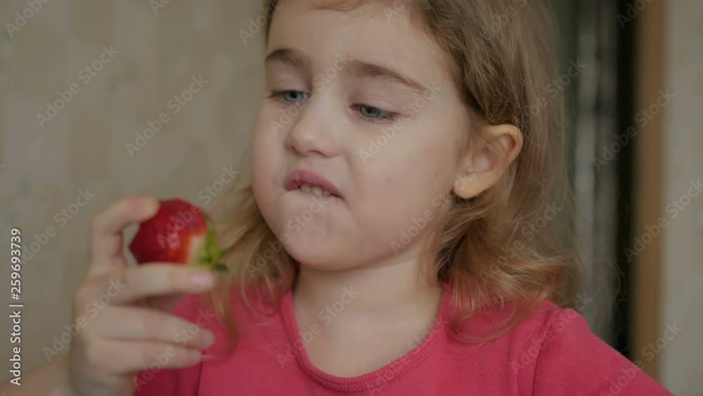 Happy child little girl drinks eats strawberries in the summer home kitchen. Happy child little girl drinks eats strawberries in the summer home kitchen.