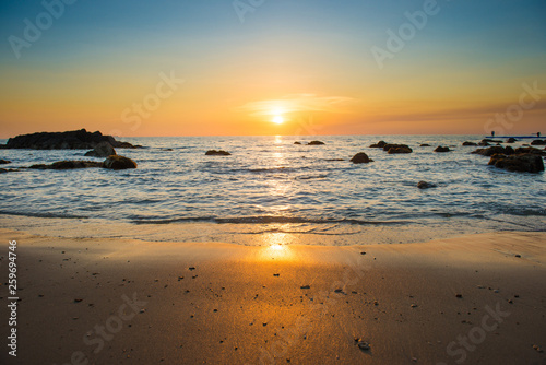 Beautiful colorful sunset landscape with sand beach  golden sun and stones at sea shore