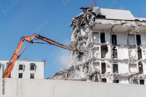 excavator-destroyer breaks the wall of the building. demolition and dismantling of the town house photo