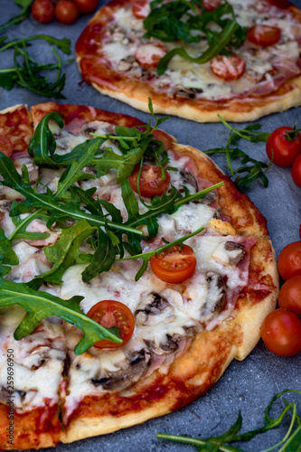 Homemade pizza with rucola and cherry tomatoes.