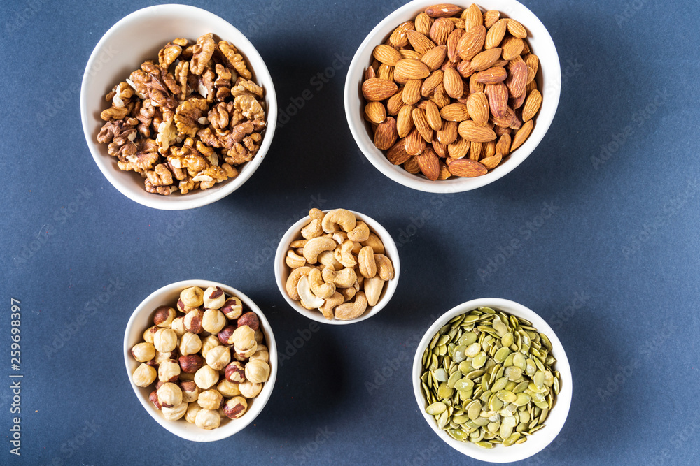 Variation of nuts in bowls on gray background. Variation of nuts in bowls on gray background.