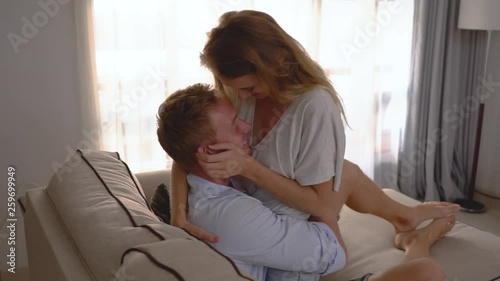 Beautiful young couple bonding and smiling while lying on the couch. affection love