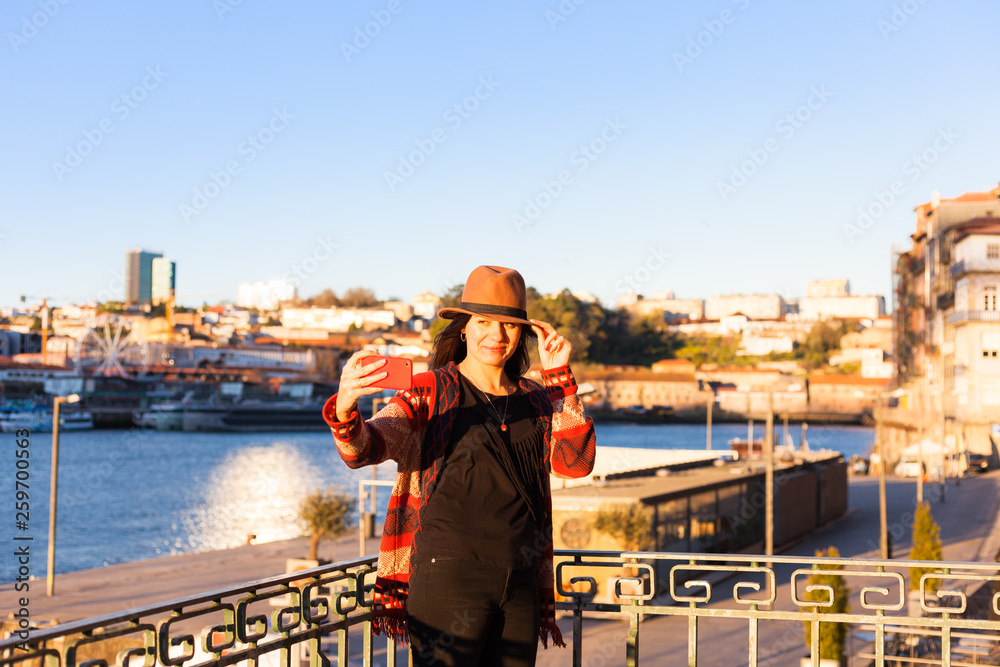 Young woman with long hair walking on city street at sunrise, wearing hat and coat, enjoying happy pleasant moment of her vacations