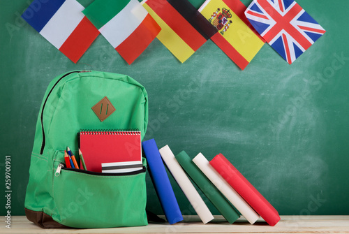 backpack, flags of Spain, France, Great Britain and other countries, books and school supplies of the blackboard photo