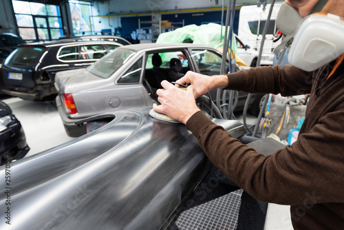 Professioneller Autolackierer schleift ein Autoteil mit der Schleifmaschine vor in einer Werkstatt - Serie Autowerkstatt © mabofoto@icloud.com