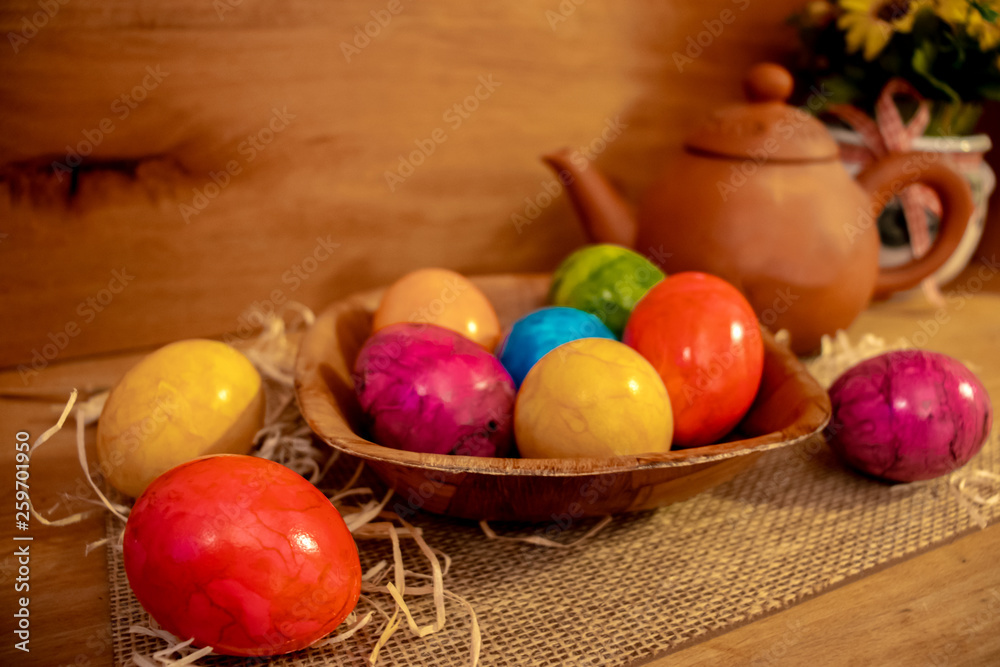 Colorful easter eggs on a basket in wooden surrounding background Colorful easter eggs on a basket in wooden surrounding background