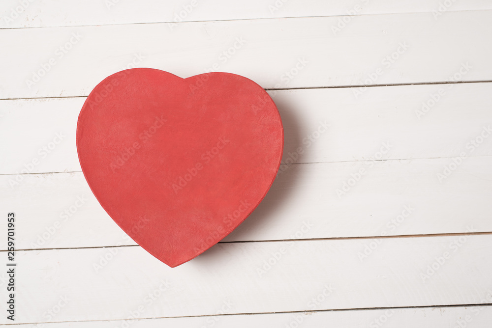 Red heart shaped box on white wooden table Red heart shaped box on white wooden table