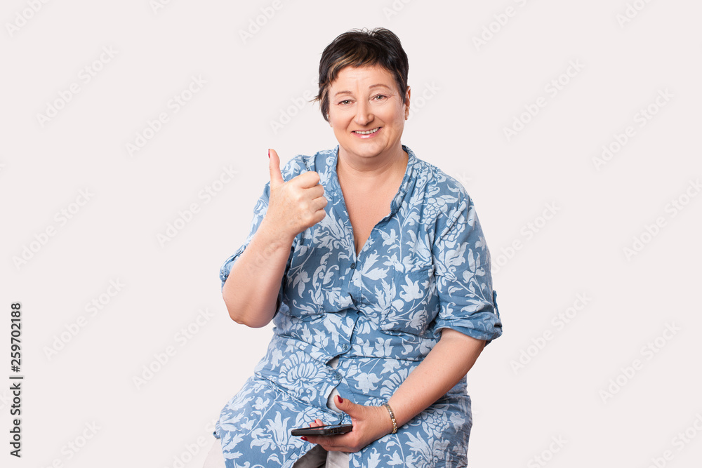 modern grandmother with a new smartphone phone, a woman is satisfied with mobile communication, a thumb to the top, showing class, everything is fine modern grandmother with a new smartphone phone, a woman is satisfied with mobile communication, a thumb to the top, showing class, everything is fine