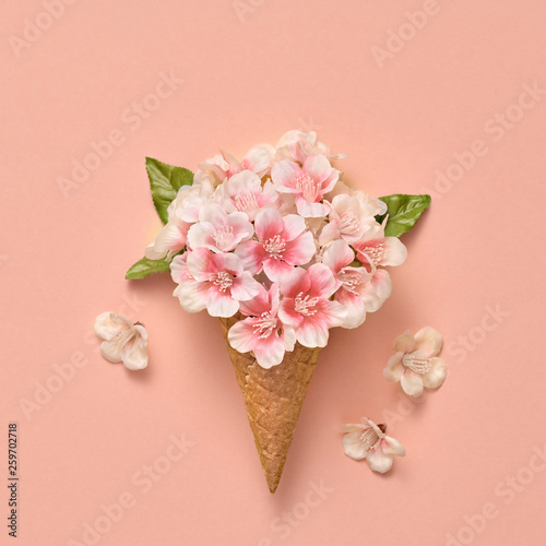 Fototapeta Naklejka Na Ścianę i Meble -  Bouquet of Flowers in Ice Cream Cone. Spring Summer Floral concept. Creative Minimal on coral. Trendy fashion art Style. Party, birthday holiday concept. Pink Flower, pastel Vanilla Color.