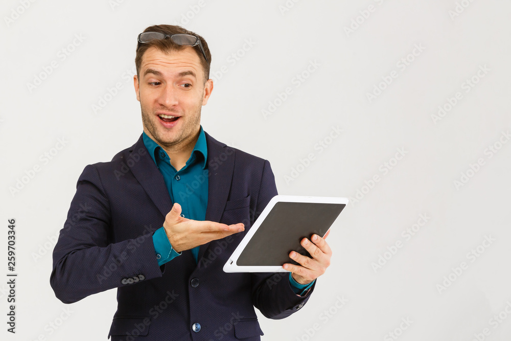 Using modern technologies. Handsome young man in shirt looking at his digital tablet and smiling while standing against background Using modern technologies. Handsome young man in shirt looking at his digital tablet and smiling while standing against background