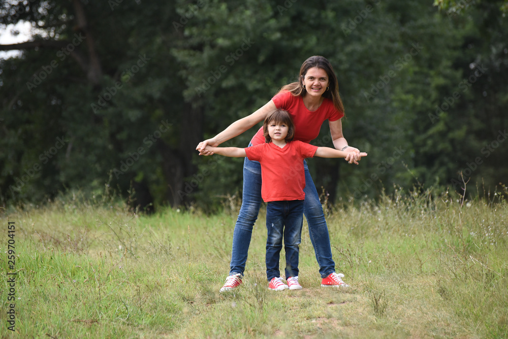 Portrait of Happy mom play with a son in park. Mother and son in red t-shirt playing outside Portrait of Happy mom play with a son in park. Mother and son in red t-shirt playing outside