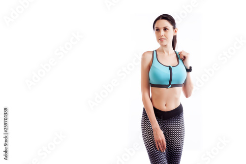 Close up of a young  slim woman athlete  in a sporty green short top and gym leggings posing and smilling on a  white isolated background in studio. Portrait of a beautiful sportswoman © Виталий Сова