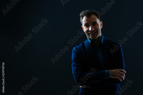 Happy smiling business man with crossed arms on black background