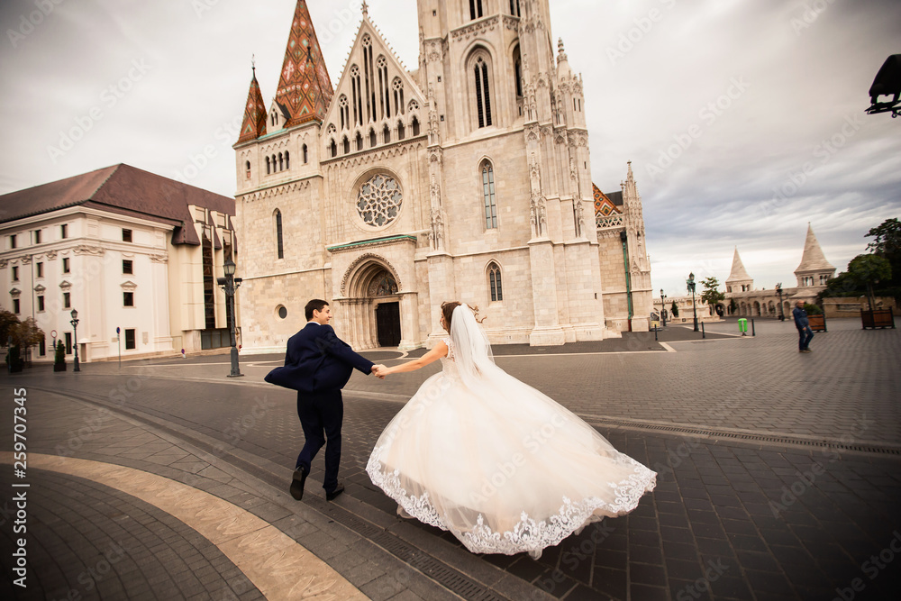 Obraz premium Young beautiful stylish pair of newlyweds walking by the Fisherman's Bastion in Budapest, Hungary