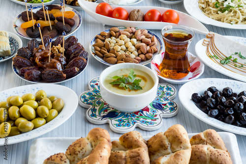 General view of Ramadan,iftar table.Setting elegant a table with soup,olives,tea,cherry tomatoes,date fruits,pistachio and Ramadan bread slices.Used blue colored Turkish motifs.