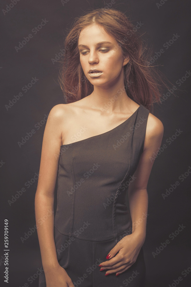 Naklejka premium Fashionable girl in golden gray tones in studio. Woman with unflappable face. Lifestyle concept in fashion world