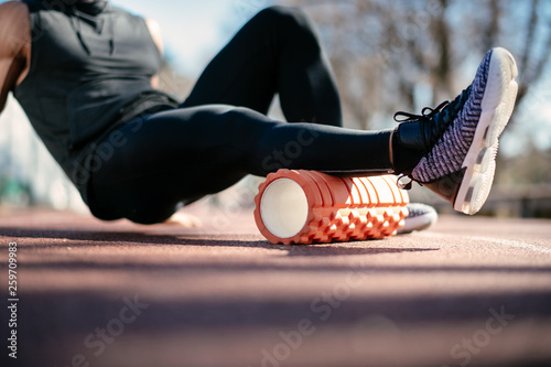 Man foam rolling. Athlete stretches using foam roller. photo