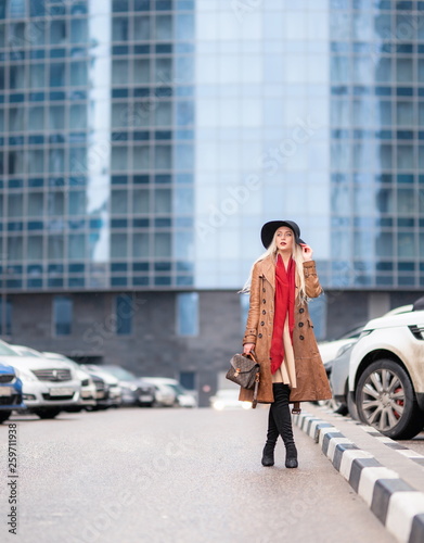 Beautiful young girl on the background of the wet streets of the spring modern city