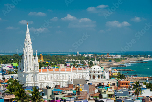 Our Lady of Ransom Shrine Church behind colorful houses on a sand beach occupied by fishing boats in Kanyakumari in India photo