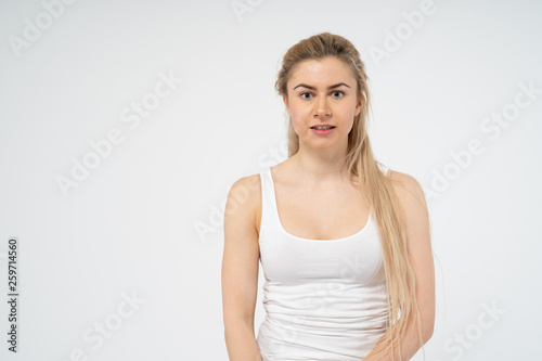 A young attractive girl looks puzzled at the camera. Isolated on white background